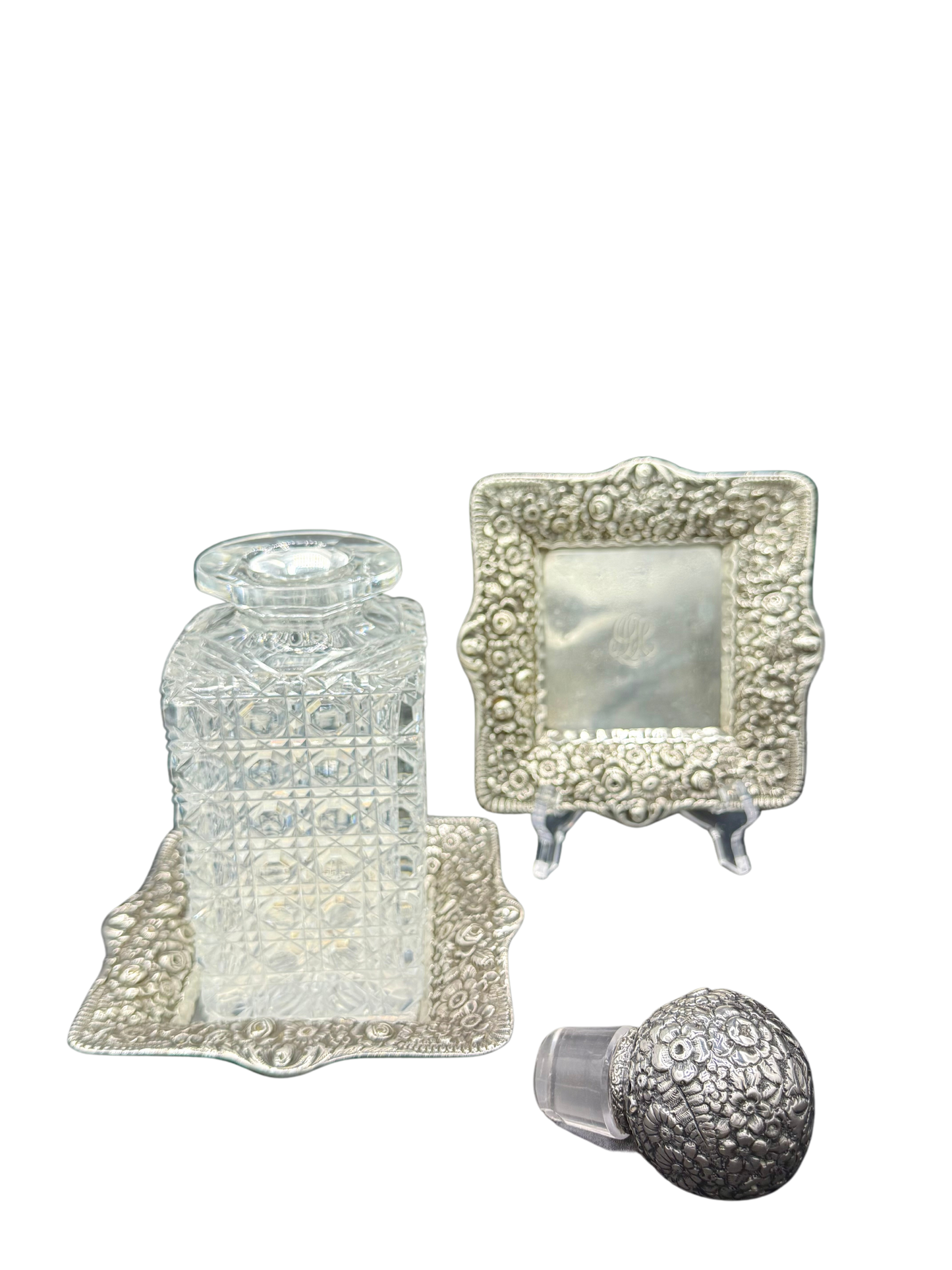 Three-piece Tiffany & Co. barware set with crystal decanter, repoussé sterling silver trays, and matching stopper