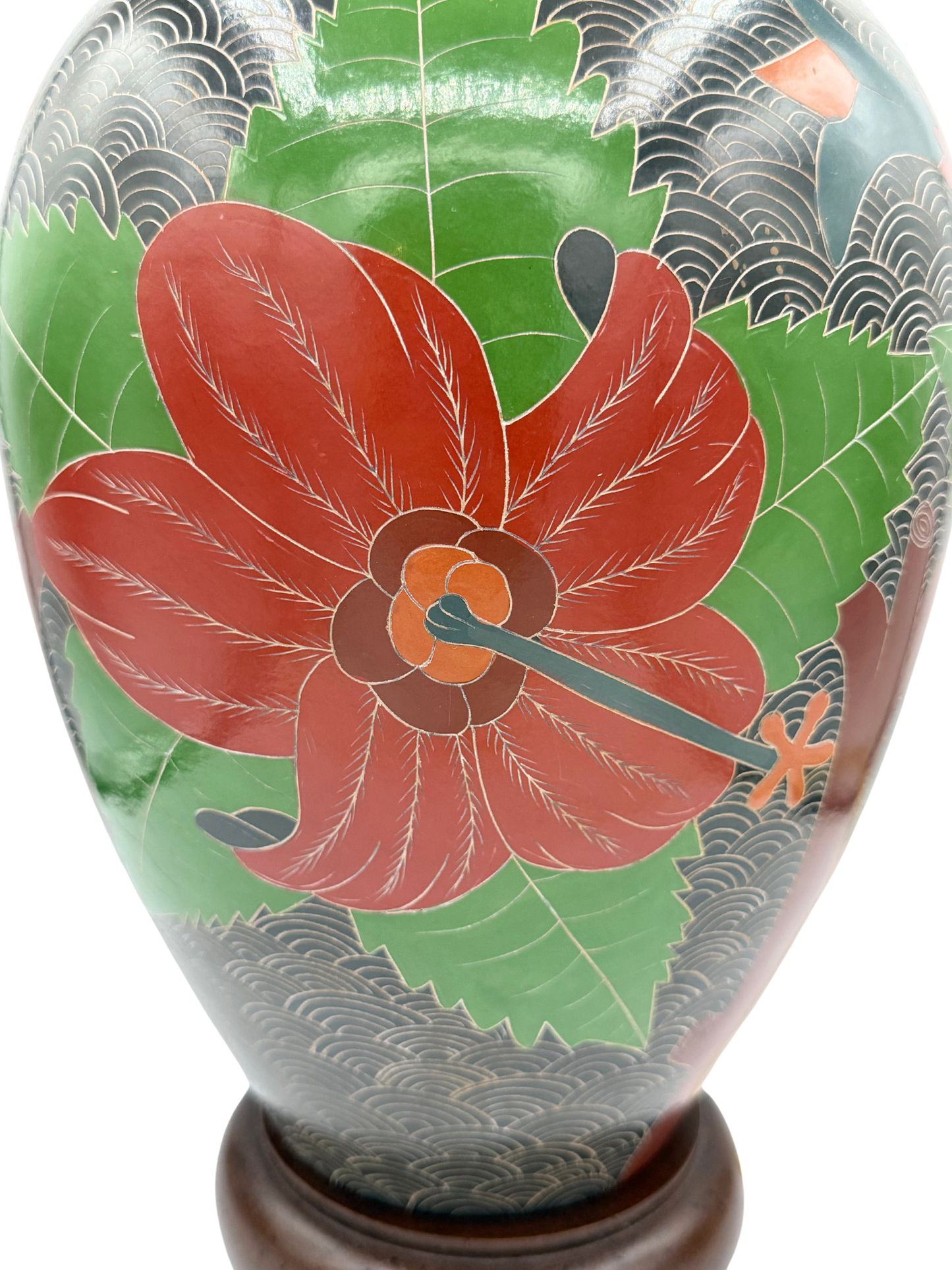Close-up of floral carving on sgraffito stoneware lamp featuring red flower and green leaves with wave pattern background
