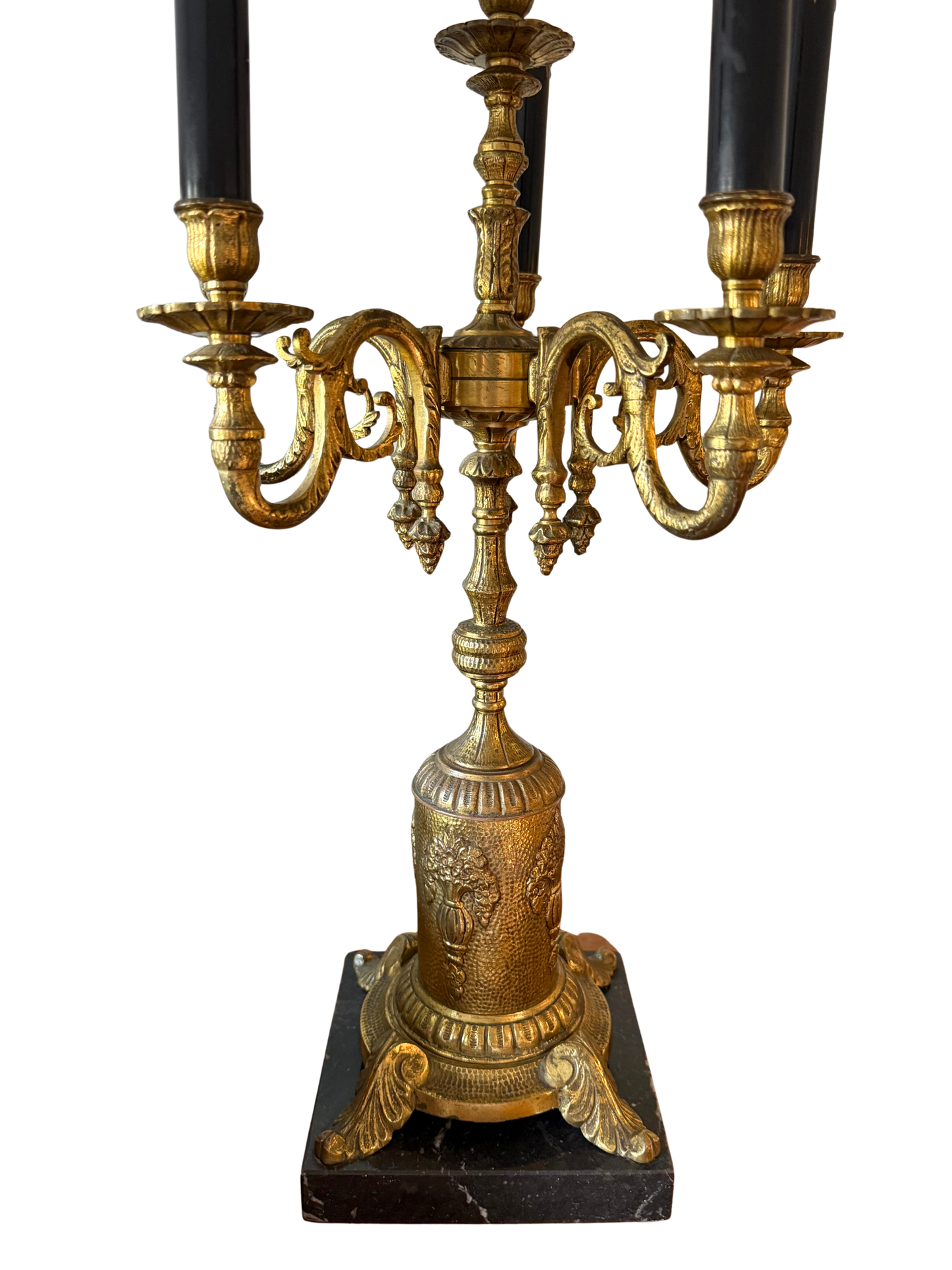 Close-up of vintage gilded brass base and scrolling candelabra arms with faux candle sleeves on a decorative table lamp.