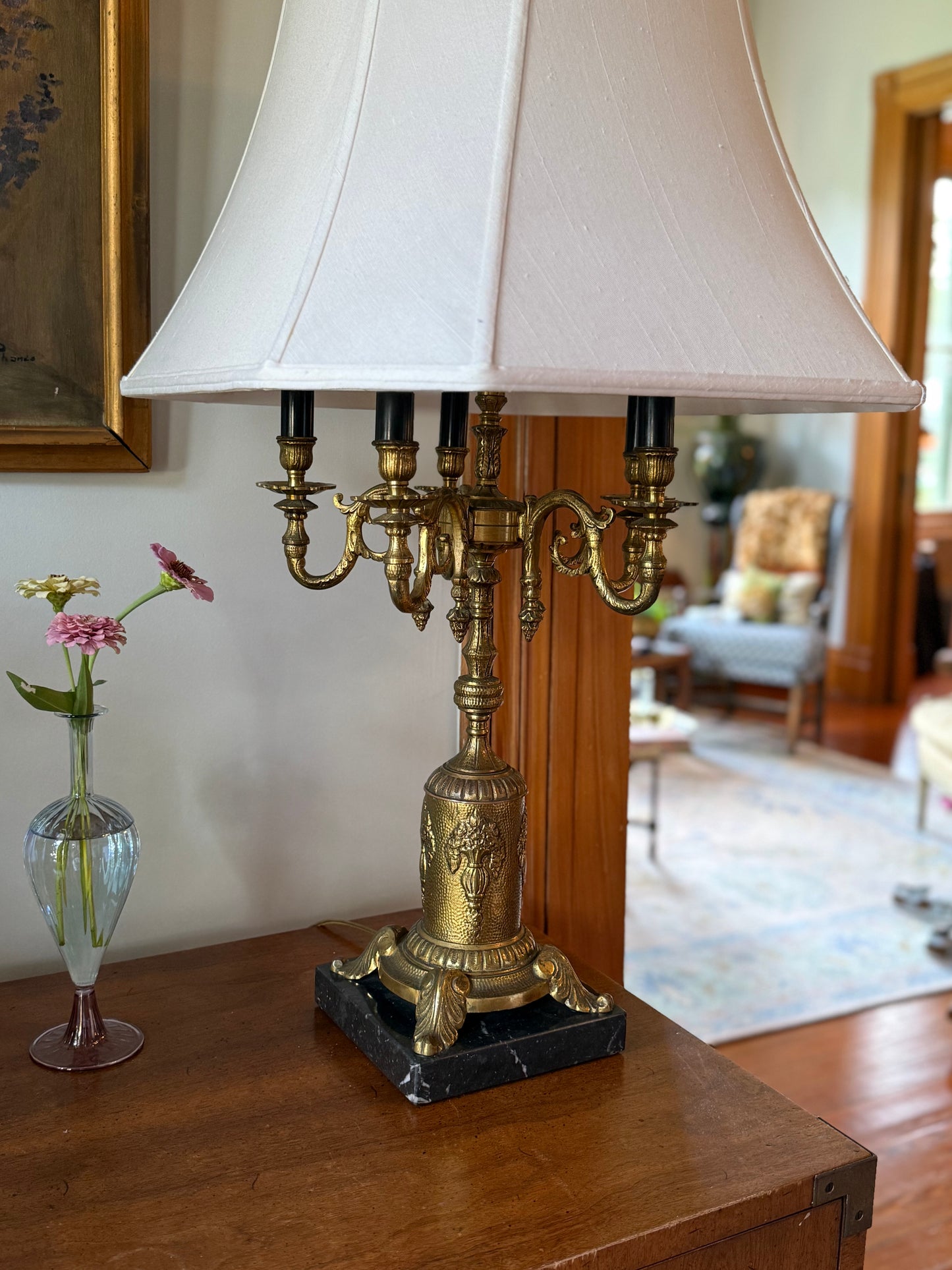 Side view of vintage neoclassical-style candelabra table lamp with six faux candle sockets and a flared fabric shade in a classic interior.