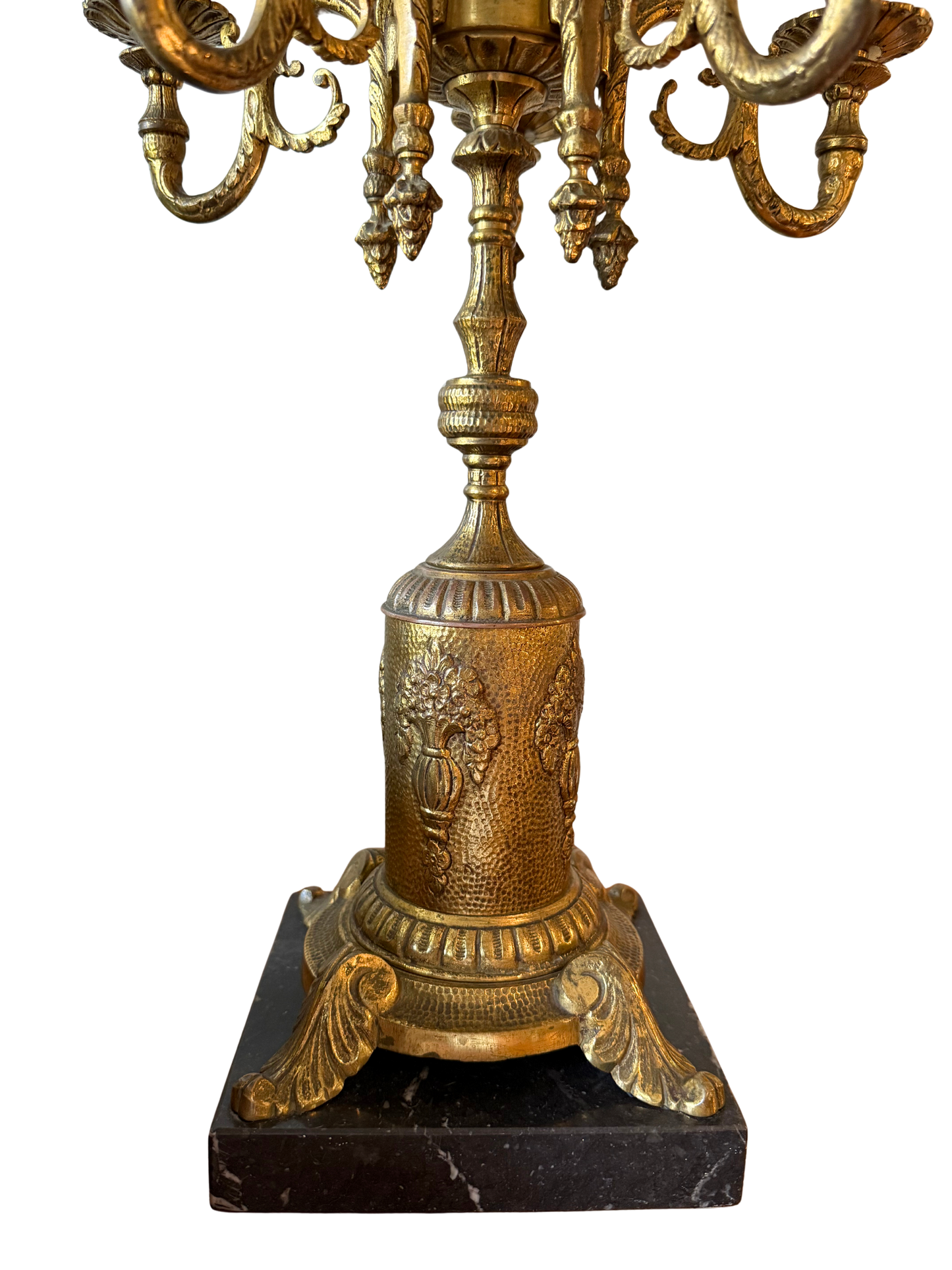 Detailed view of embossed floral motif on vintage gilt brass lamp base with acanthus claw feet and black marble plinth.