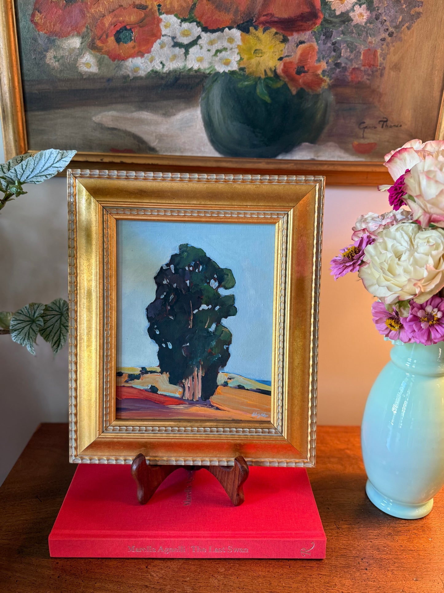 Styled display of framed Peggy Olsen California landscape painting in interior setting, featuring eucalyptus tree motif.