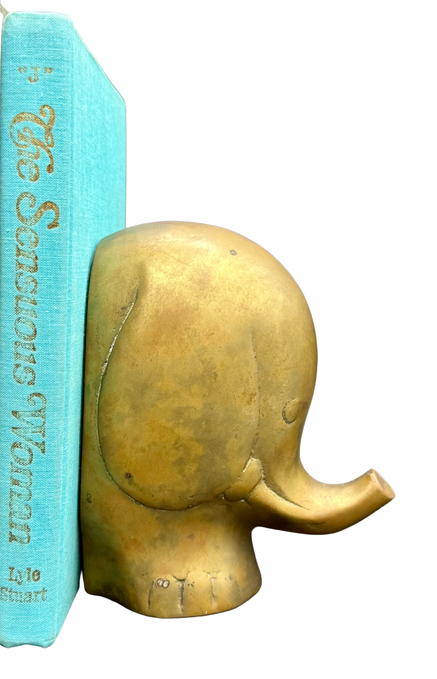 Close-up of mid-century brass elephant bookend holding turquoise book