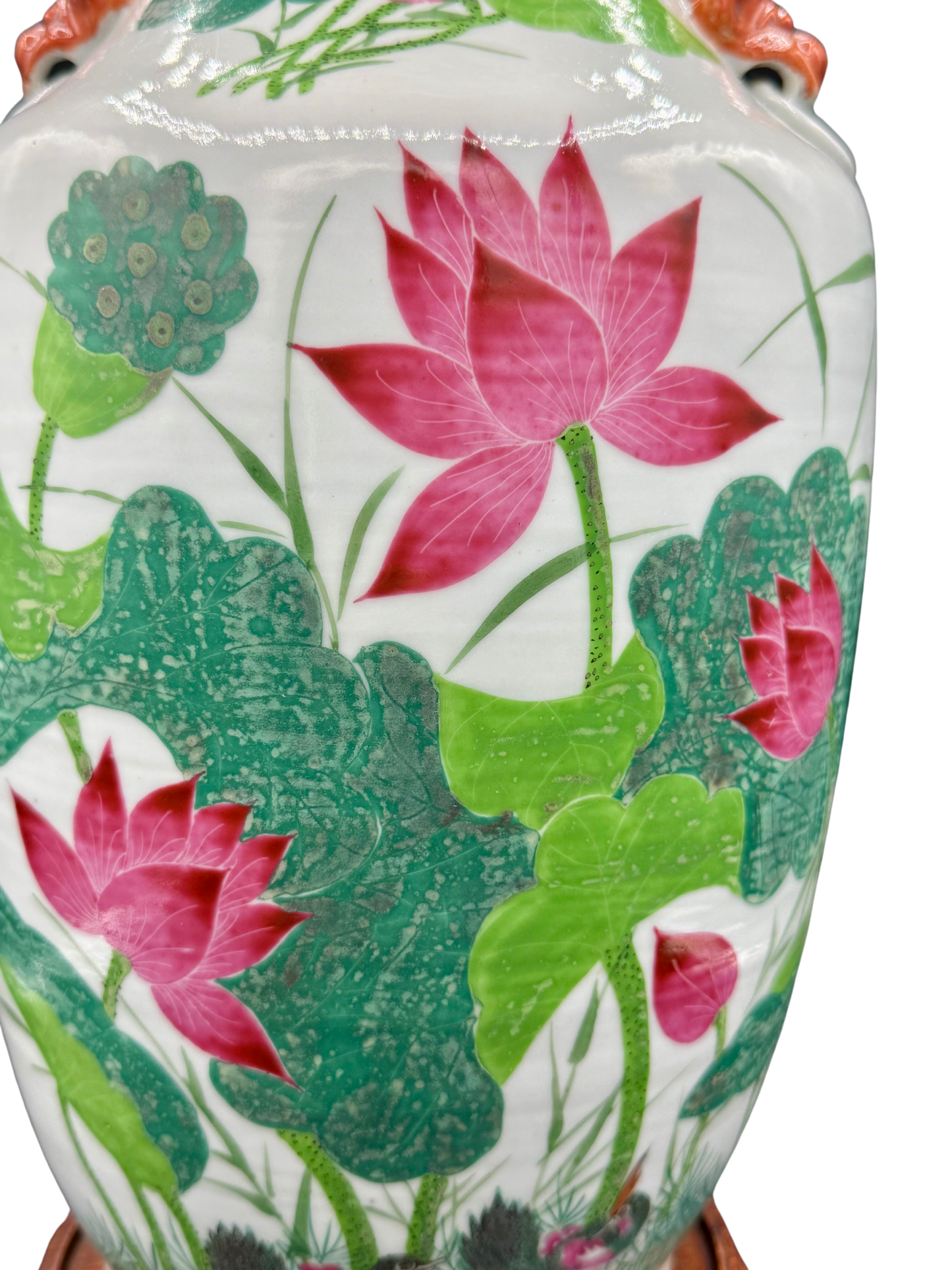 Close-up of red lotus flowers and green foliage on antique Chinese vase