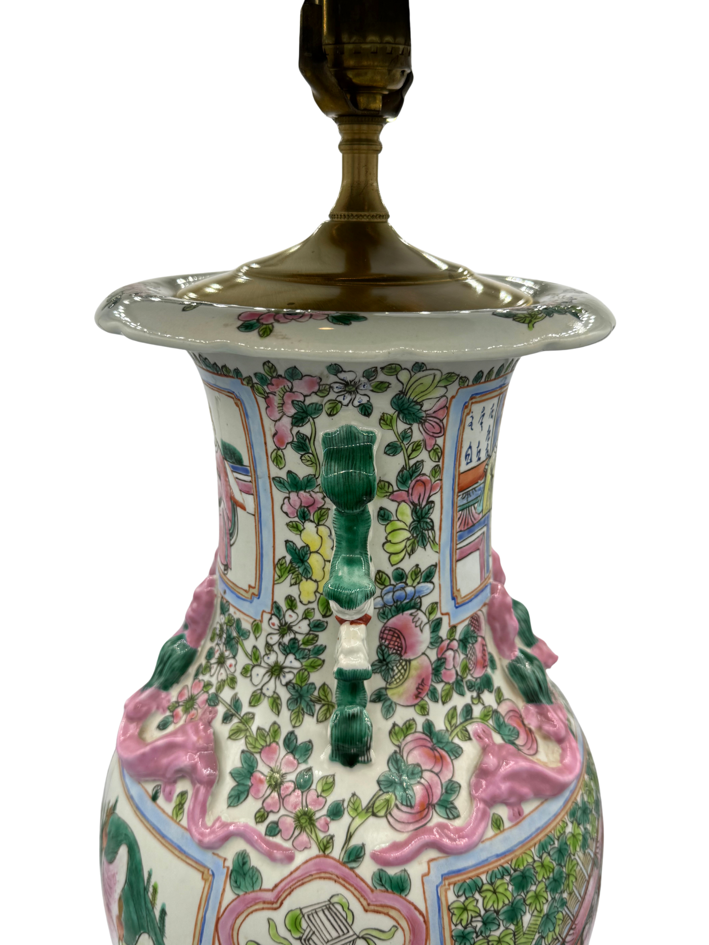 Close-up of the top of a chinoiserie porcelain table lamp showing applied dragons, florals, and a brass socket, with vibrant famille rose detailing.