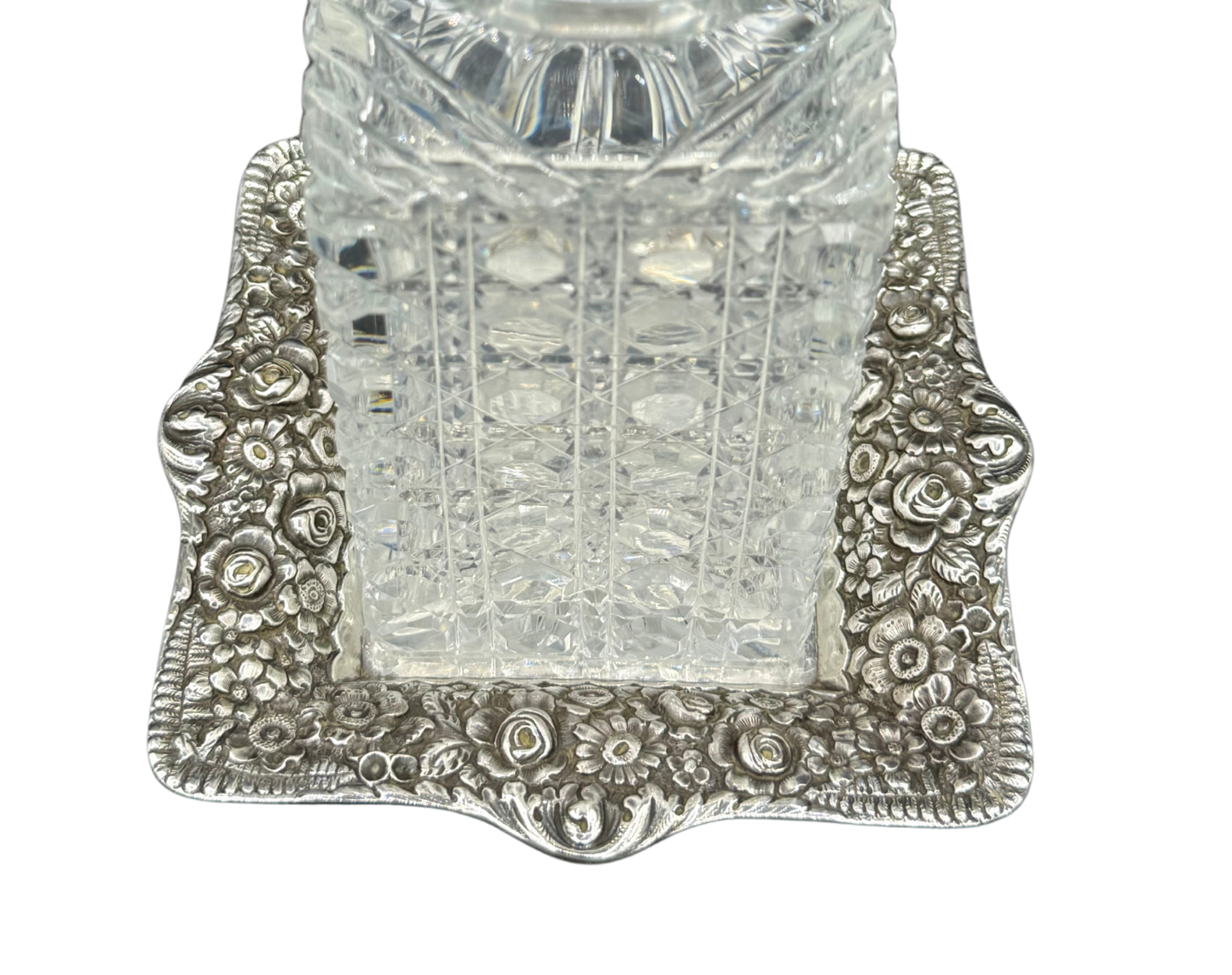 Detailed view of Tiffany repoussé sterling tray with cut crystal decanter base, highlighting floral border
