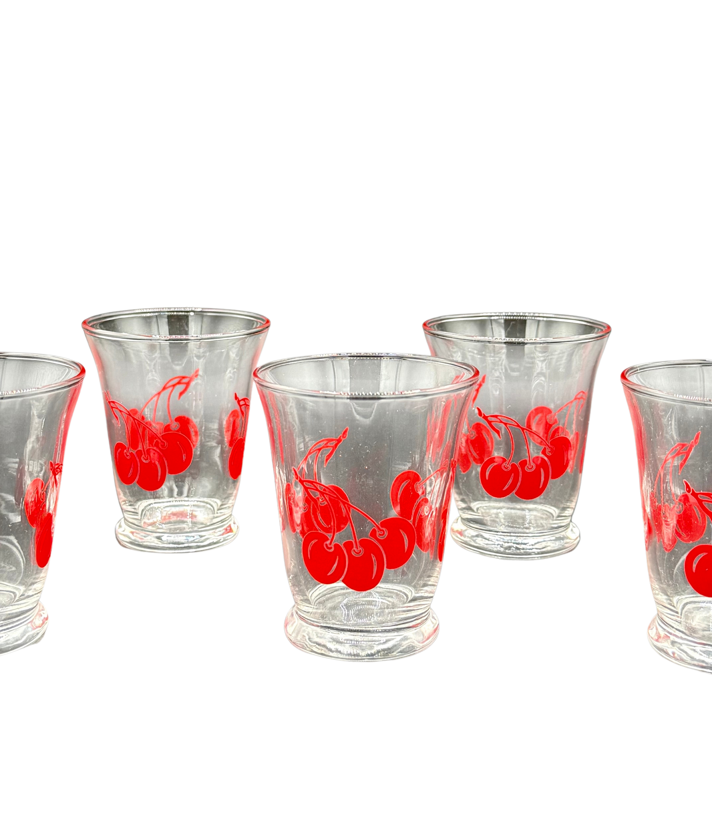 Close-up of vintage flared juice glasses with bold red cherry graphics, collectible 1940s–1960s kitchenware”