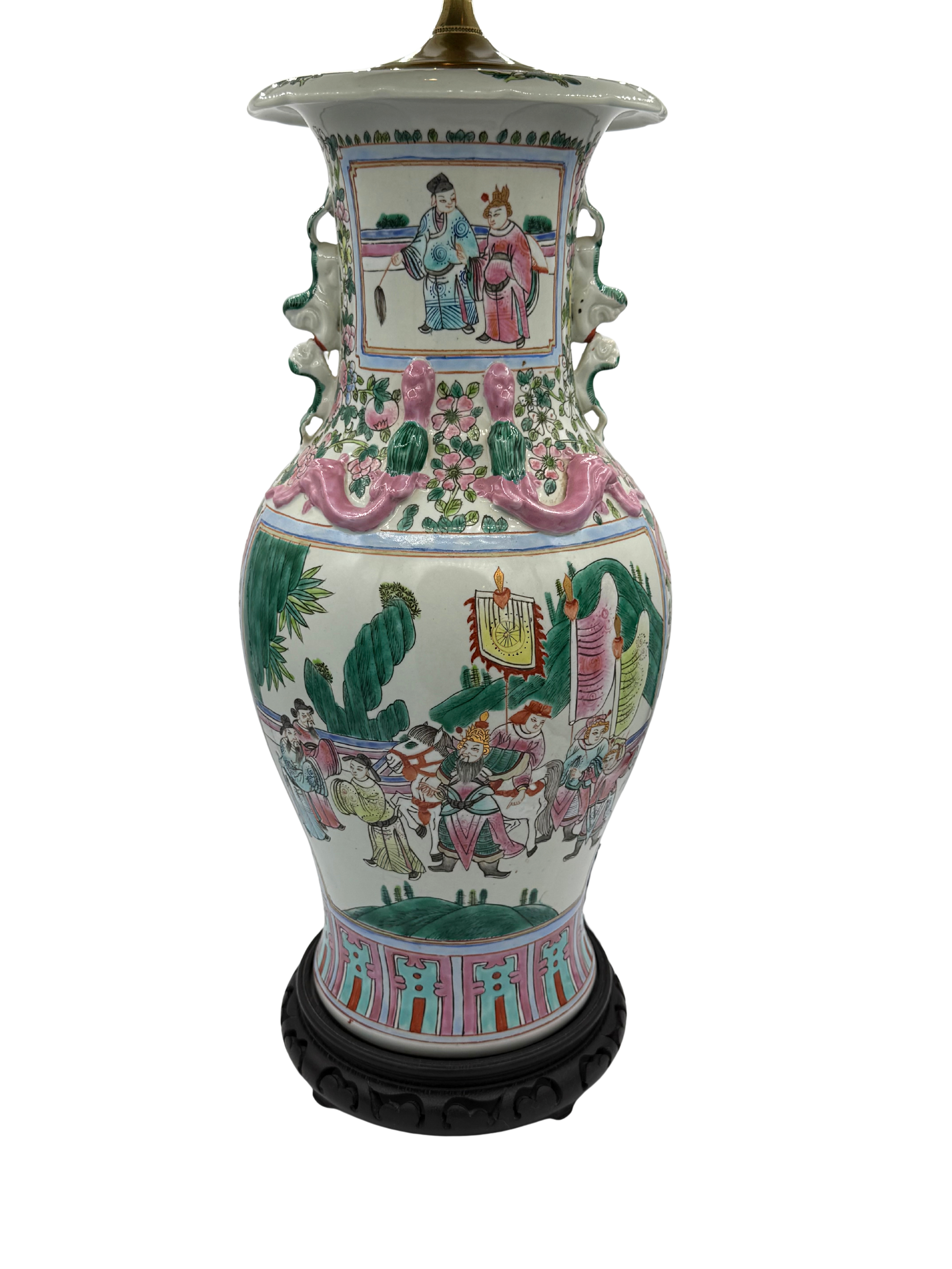 Front-facing image of vintage Chinese export table lamp with famille rose painting, high-relief dragons, and decorative foo dogs, on wooden base.