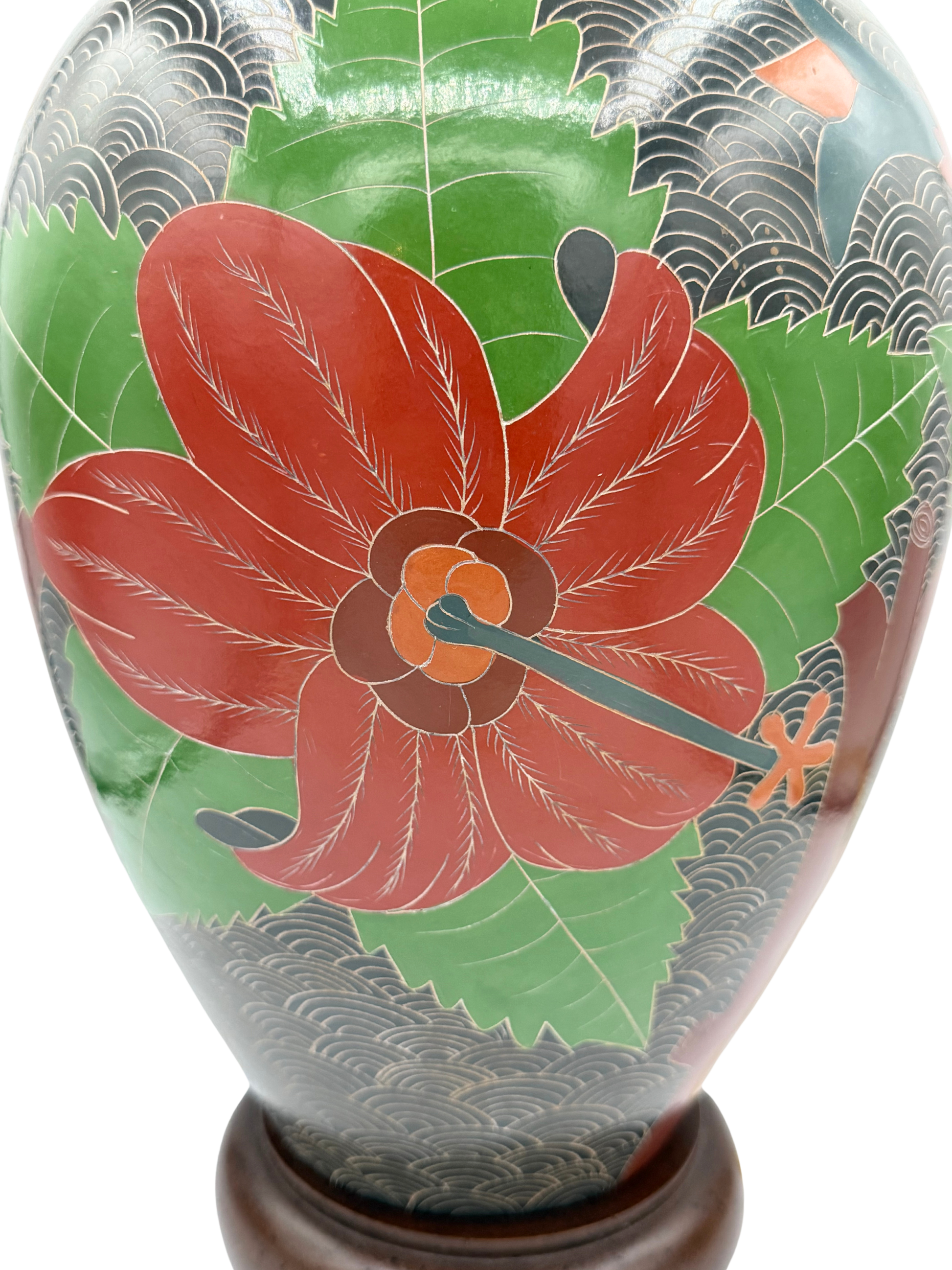 Close-up of floral carving on sgraffito stoneware lamp featuring red flower and green leaves with wave pattern background