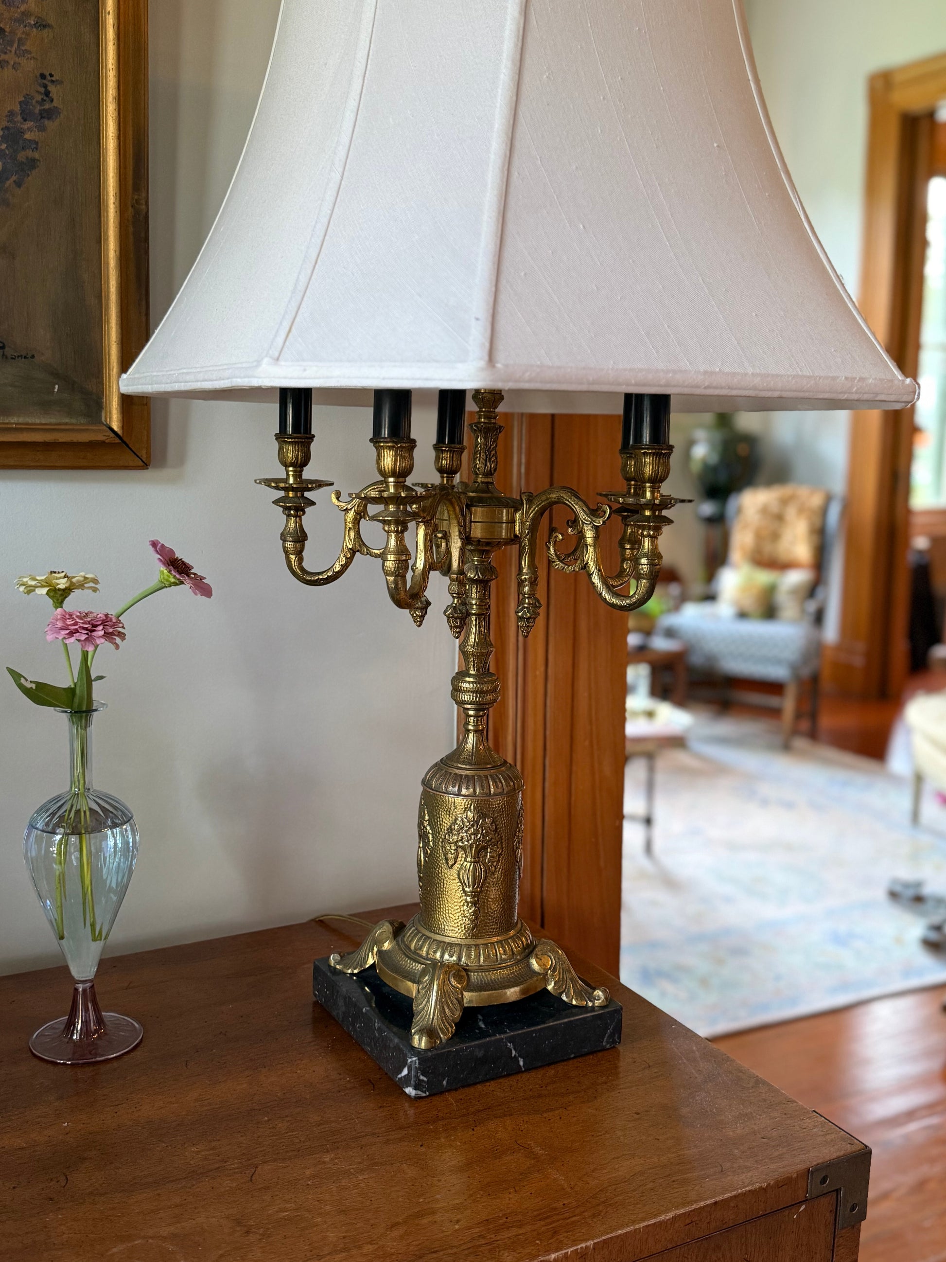 Side view of vintage neoclassical-style candelabra table lamp with six faux candle sockets and a flared fabric shade in a classic interior.