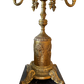 Detailed view of embossed floral motif on vintage gilt brass lamp base with acanthus claw feet and black marble plinth.