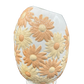 Front view of vintage daisy-embossed ceramic vase in peach and cream tones with glossy glaze.