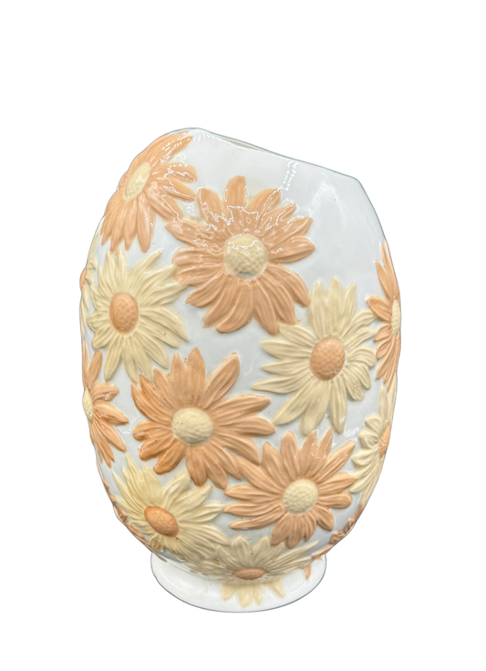 Front view of vintage daisy-embossed ceramic vase in peach and cream tones with glossy glaze.