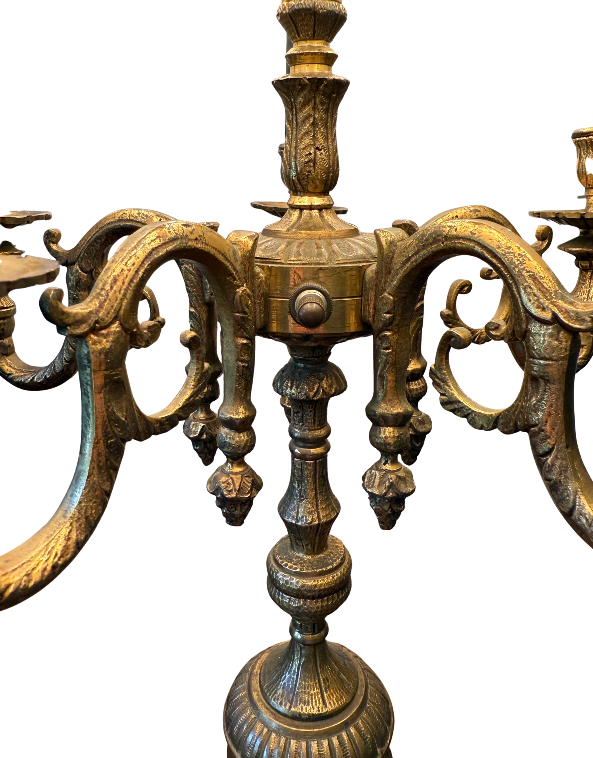 Close-up of vintage brass candelabra lamp center column and ornate scrolled arms with decorative drop finials.
