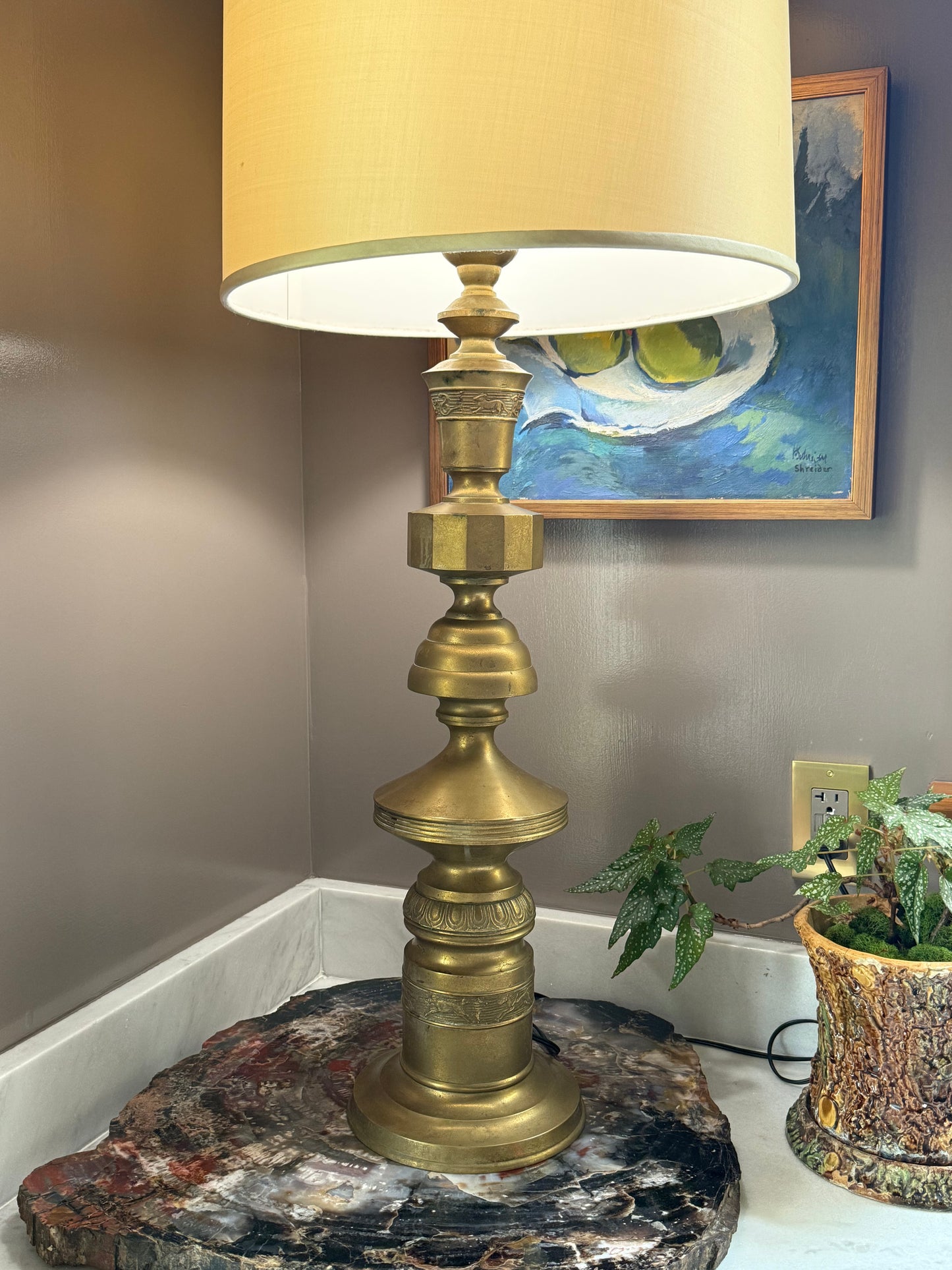 Hollywood Regency brass table lamp styled in interior with natural stone base, showing dramatic scale and sculptural form, attributed to Marbro