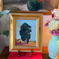 Styled display of framed Peggy Olsen California landscape painting in interior setting, featuring eucalyptus tree motif.