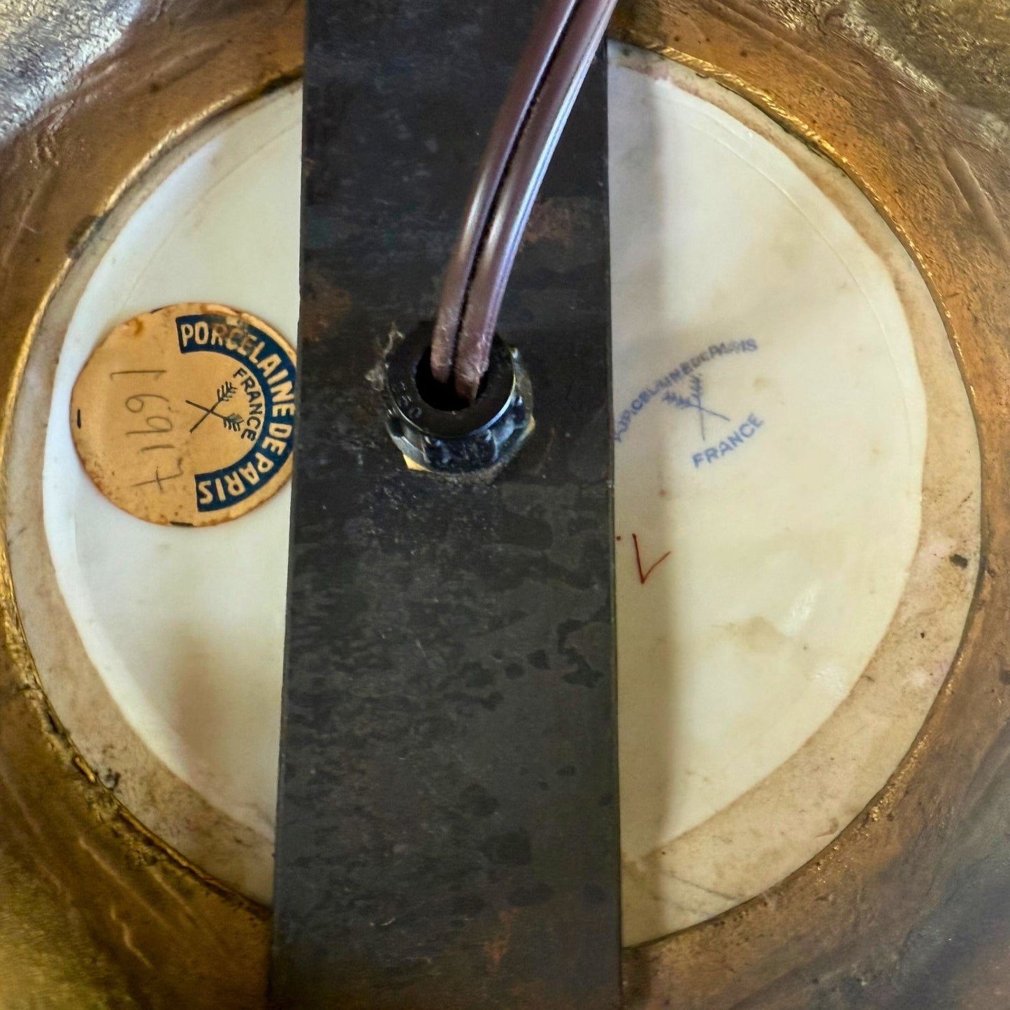 Close-up of a metal object with 'Porcelaine de Paris' branding on a textured background.