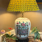 Vintage Chinese ginger jar lamp with hand-painted Famille Rose floral basket design, shown with yellow pleated shade and styled on a marble table with flowers
