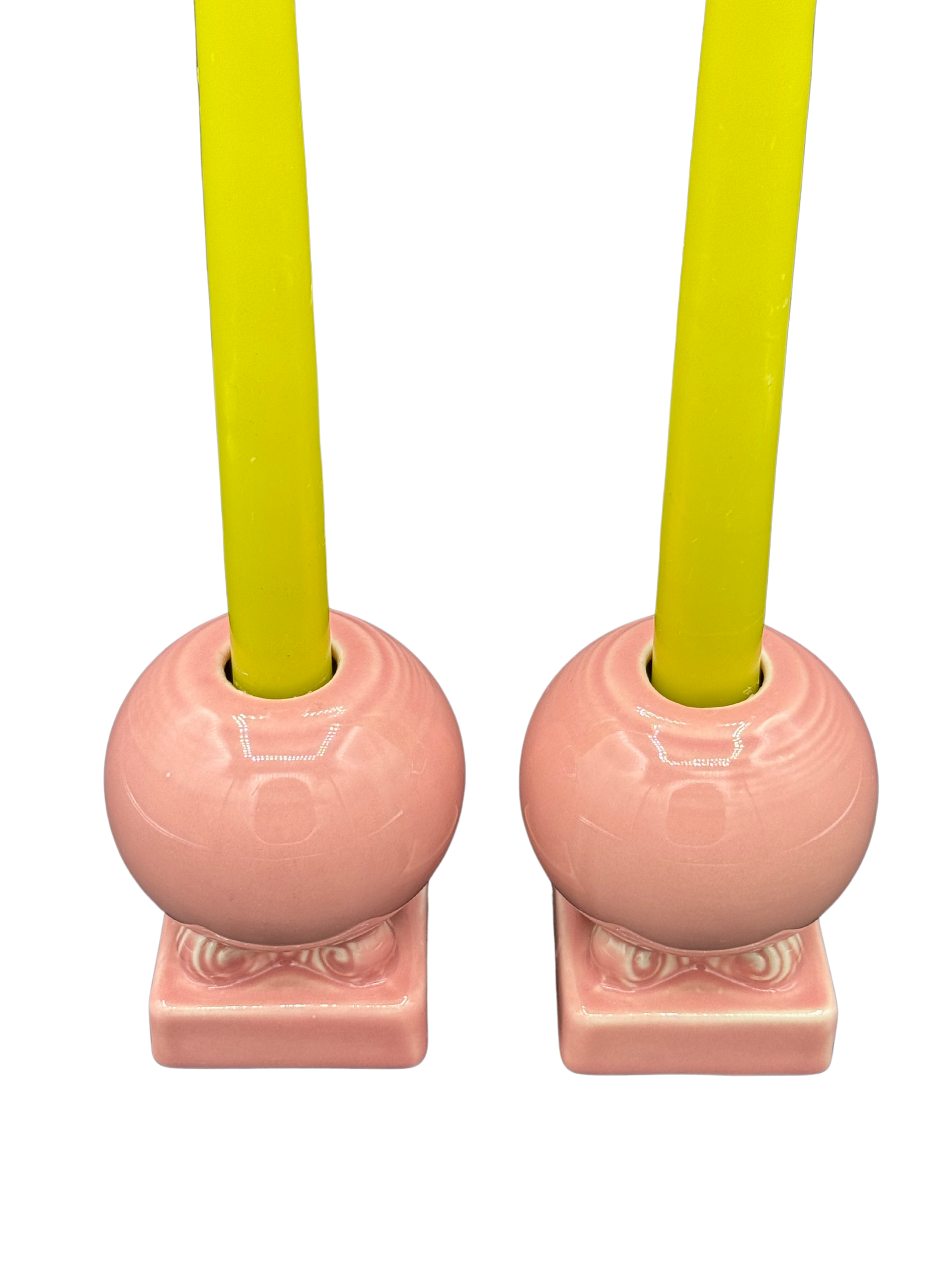 Overhead view of pink Fiestaware candle holders styled with bright taper candles