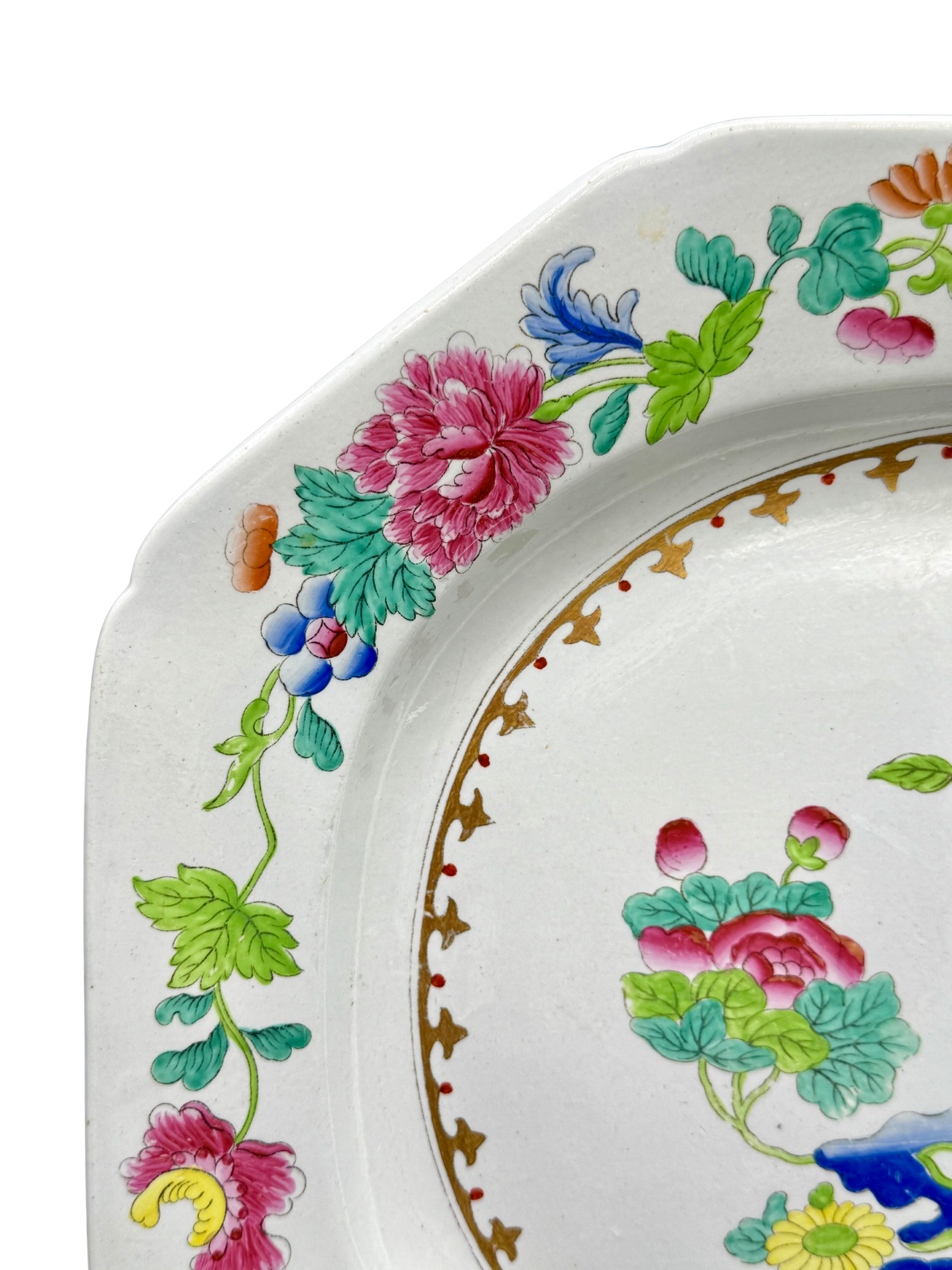 Close-up of vibrant pink peony and foliage on floral rim of antique Spode chinoiserie platter.