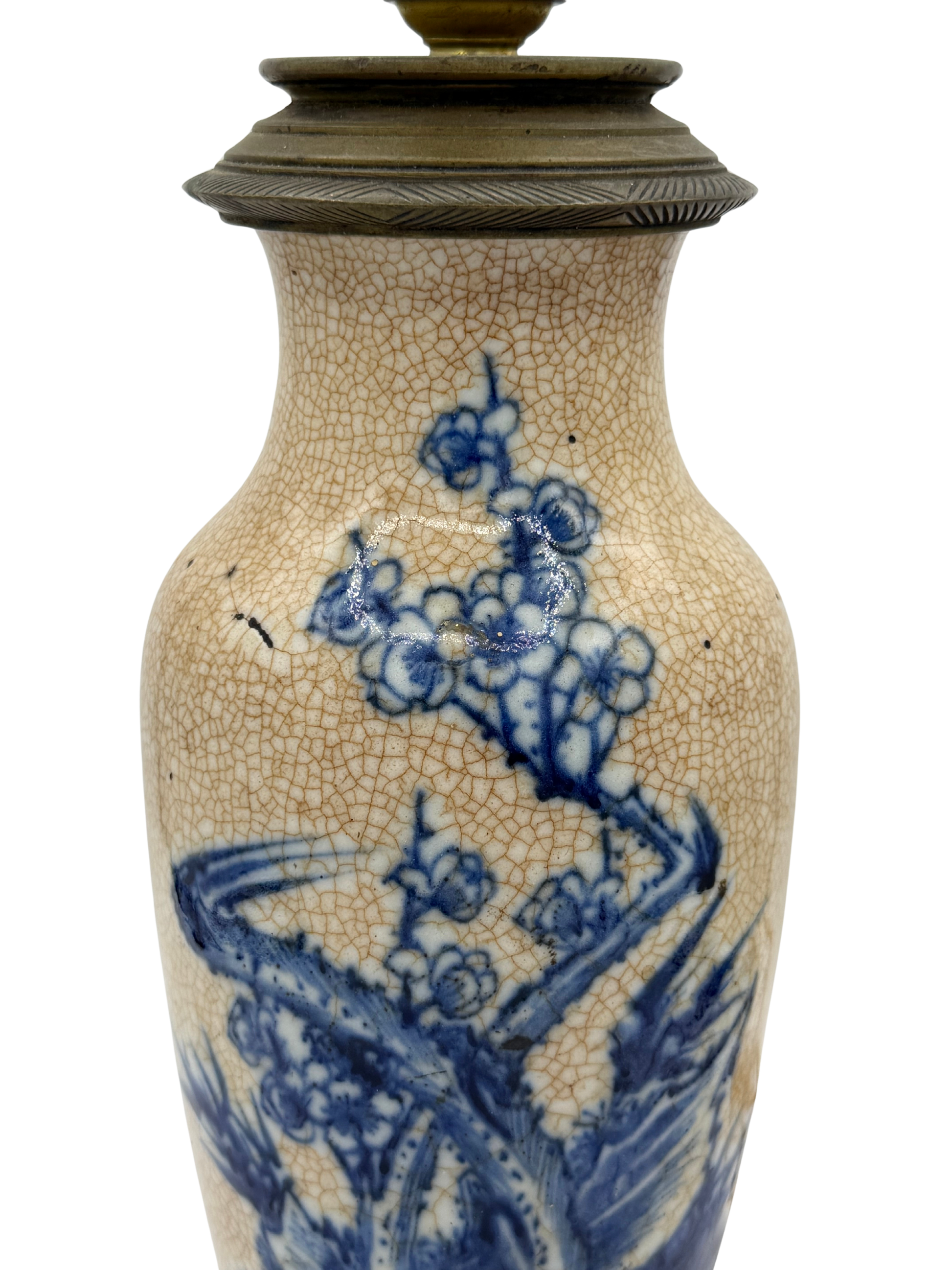 Close-up of French ceramic lamp showing hand-painted prunus blossoms in cobalt blue with visible minor crack in glaze.