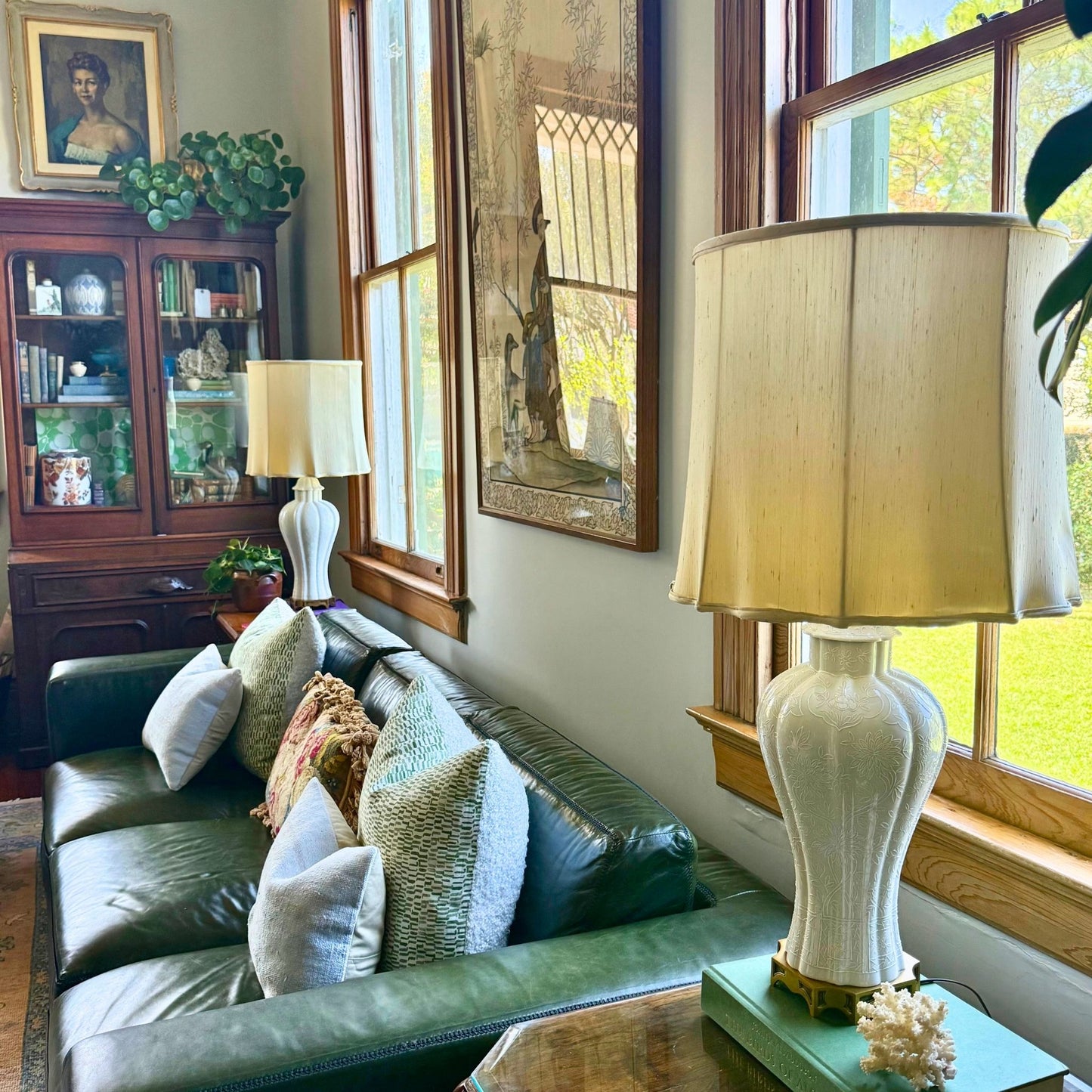 Living room with green sofa, lamp, and decorative items near a window.