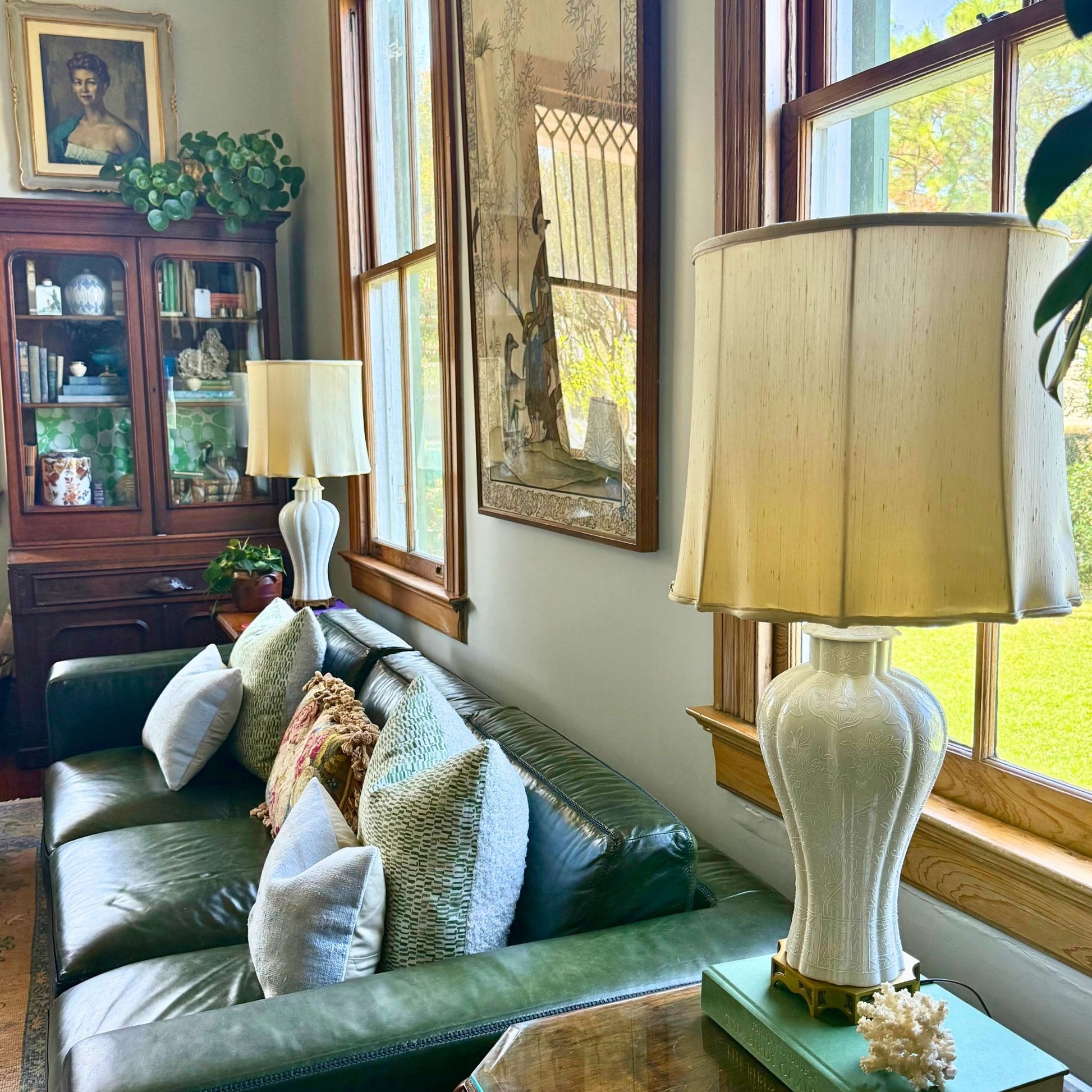 Living room with green sofa, lamp, and decorative items near a window.